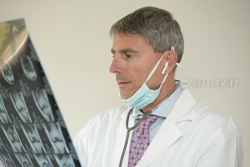 新型冠状病毒肺炎医院。医生肖像外科口罩和听诊器检查病人的x光