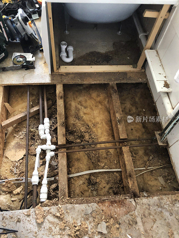 水损坏的浴室刨花板地板，漏水孔，铜管和塑料连接器，中央供暖系统，住房问题概念