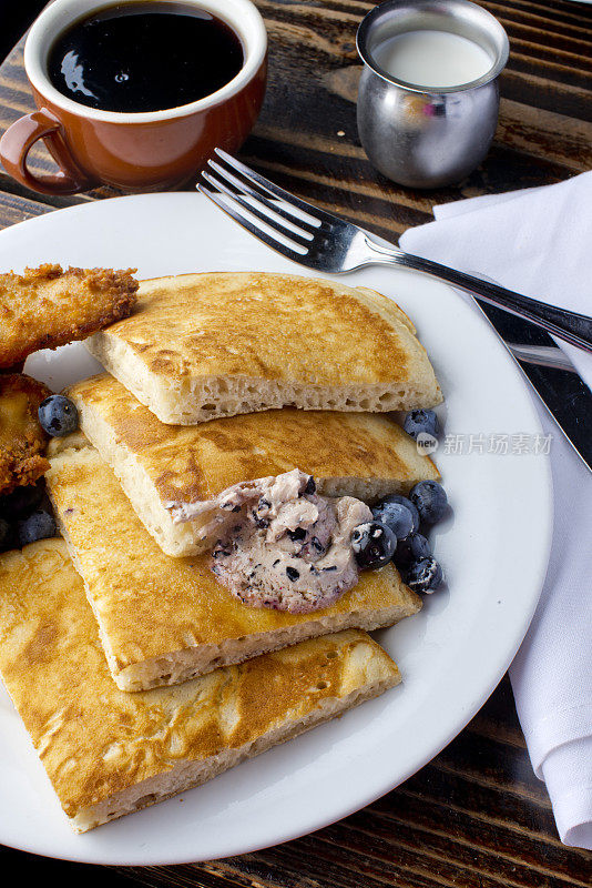蓝莓酪乳煎饼配浆果黄油和脆脆的南方炸鸡。经典的美国早餐或早午餐的最爱。自制煎饼配黄油和枫糖浆。