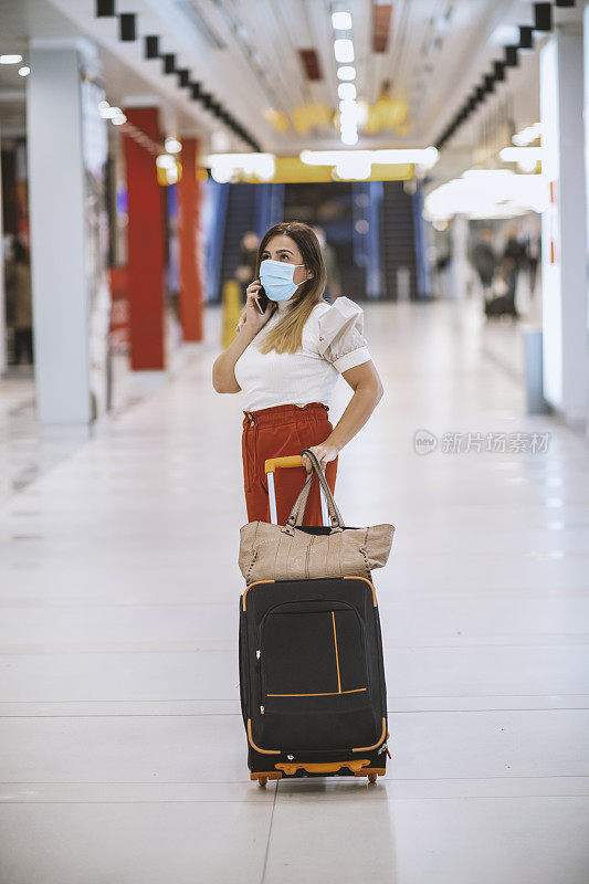 年轻的女游客戴着保护面罩使用电话