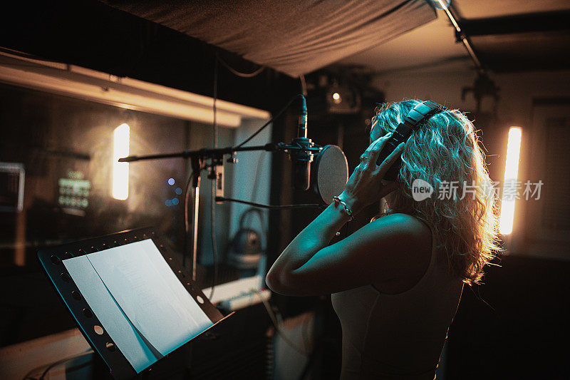 在专业音乐工作室录制歌曲的年轻女歌手