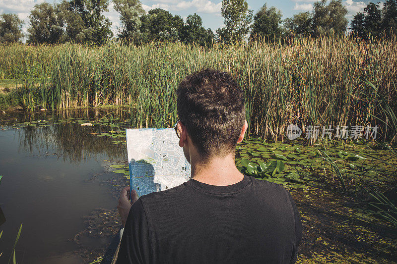 一个年轻人在户外看地图找路的照片