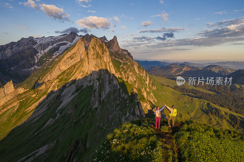 徒步旅行者在山顶击掌的无人机视图