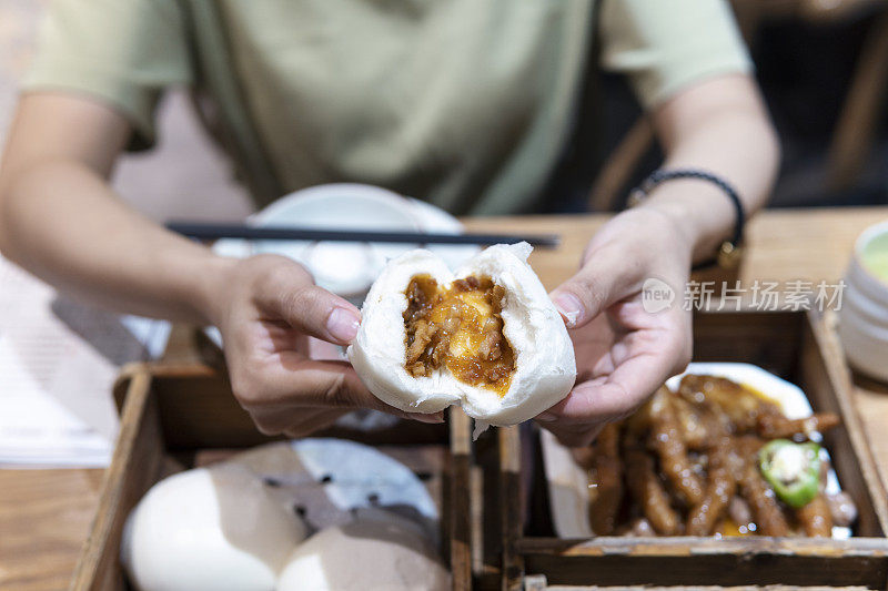 一位亚洲妇女正在一家广东餐馆里撕茶烧包