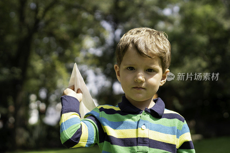 一个小男孩在一个阳光明媚的日子里玩纸飞机