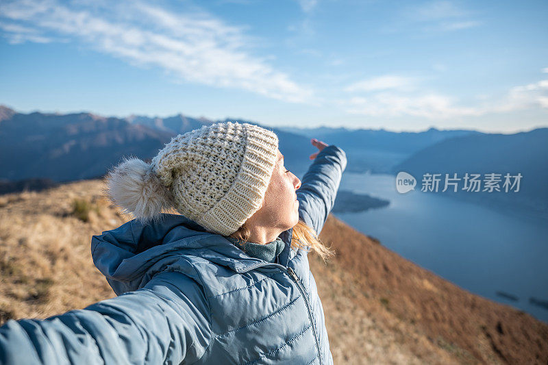 一个徒步旅行者双臂伸开站在山顶上