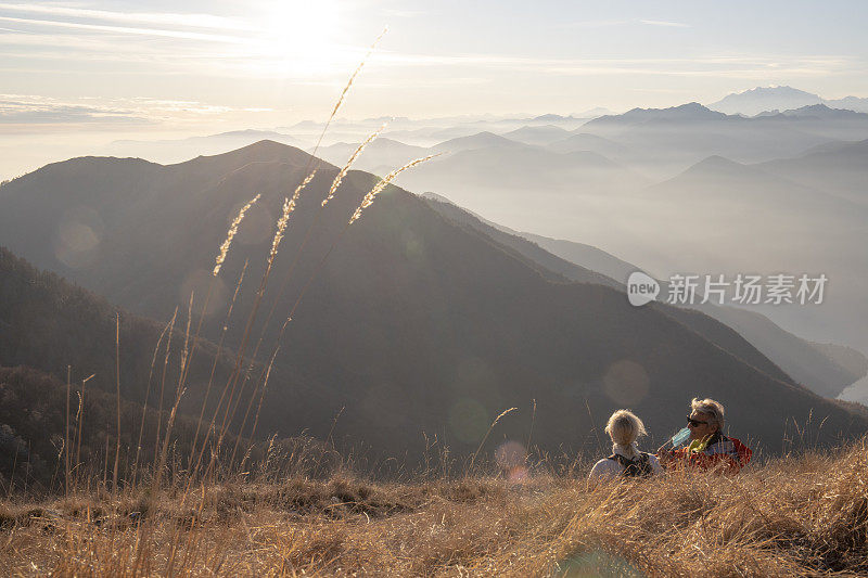 清晨，一对成熟的徒步旅行夫妇在长满青草的山坡上放松