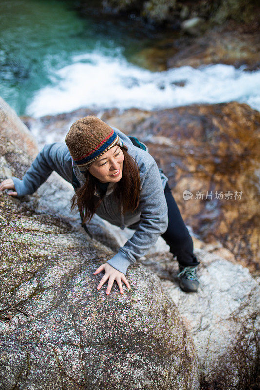 一名妇女在汹涌的水面上攀登悬崖