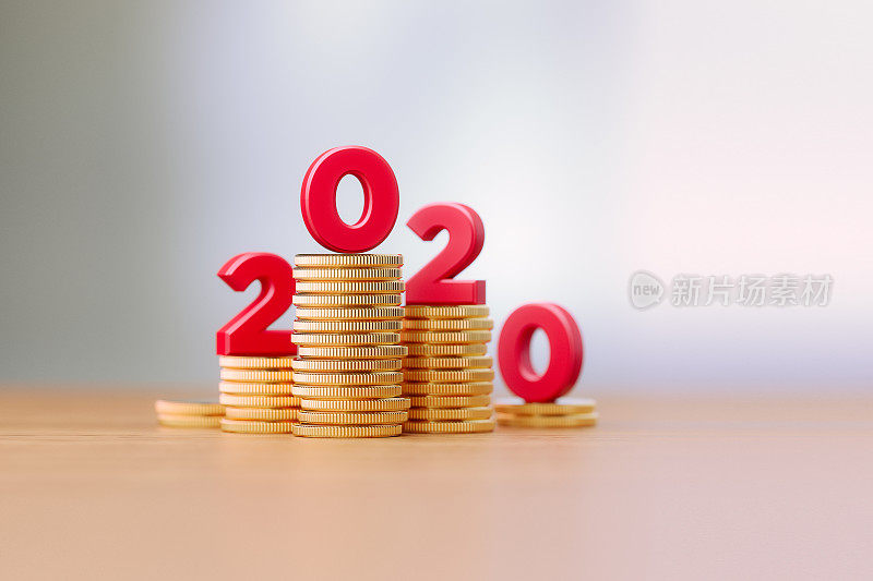 红色字母坐在硬币堆上，在背景散焦之前写2020