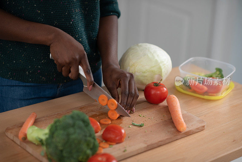 一位面目全非的非裔美国妇女切菜和包装蔬菜