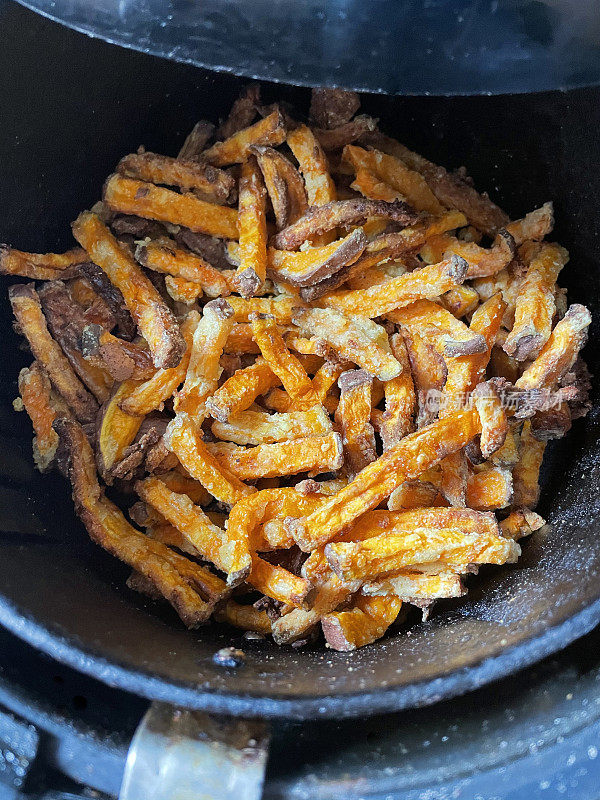 新鲜的薯片在空气中炸成金黄色，是零食烹饪的更健康的选择