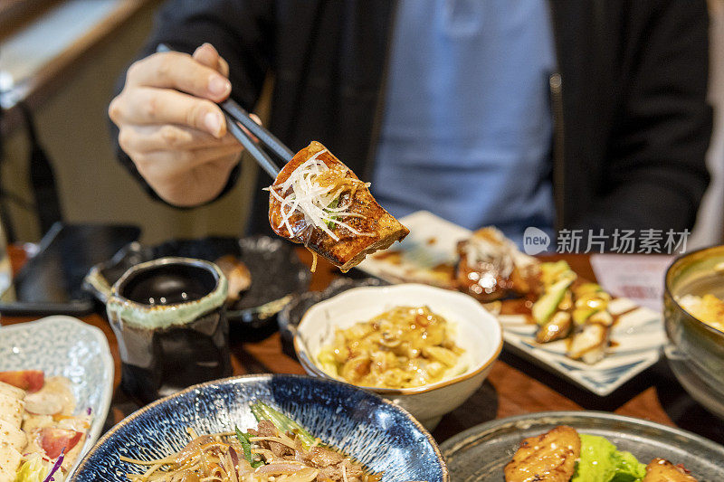 在日本餐馆吃油炸鹅肝寿司的男人