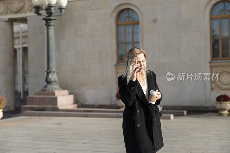 女商人在户外散步时使用智能手机