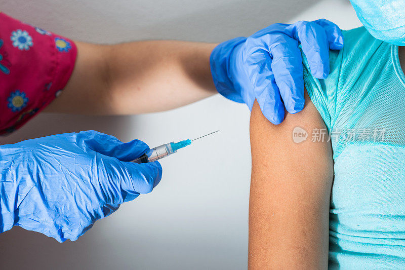 儿童护士在注射棕色小女孩的手臂，医生戴着橡胶手套在注射COVID-19或流感疫苗。医疗健康和流行病概念
