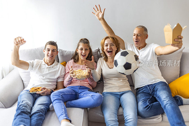 在家里观看足球比赛和庆祝进球的球迷家庭