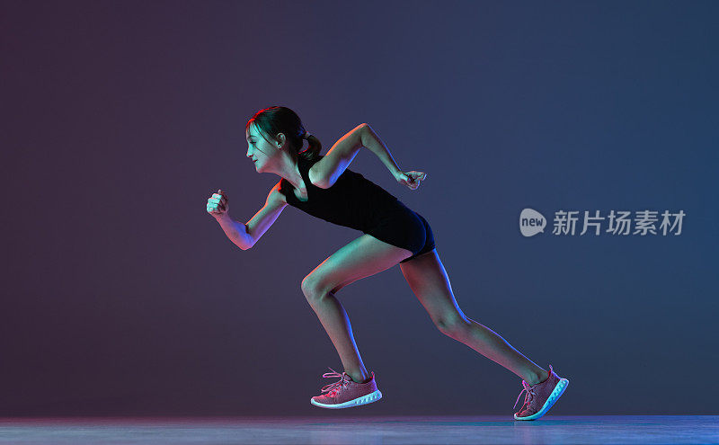 女孩的肖像，职业运动员，跑步训练孤立的梯度蓝色紫色背景在霓虹灯
