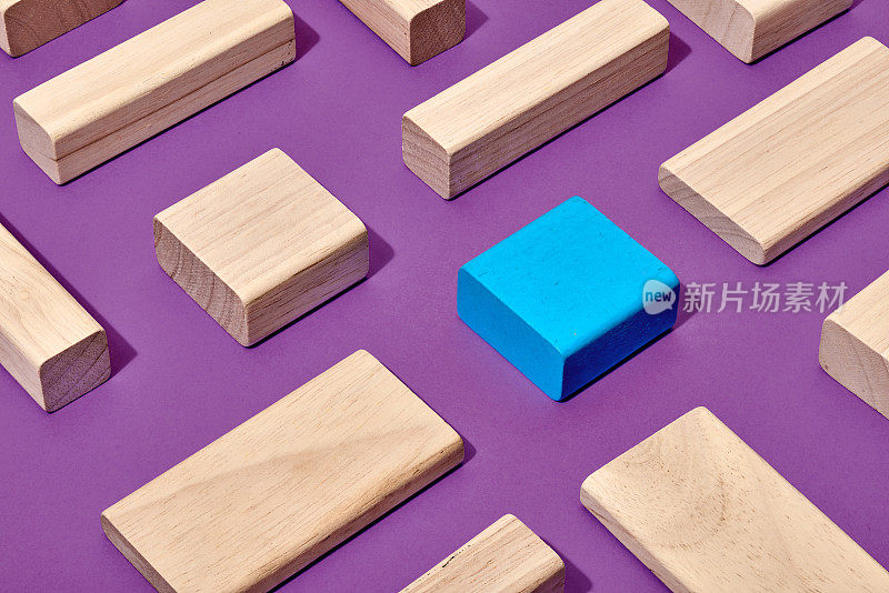 一个蓝色的矩形木块和六个木色木块在紫色的背景上形成抽象图形来区分概念
