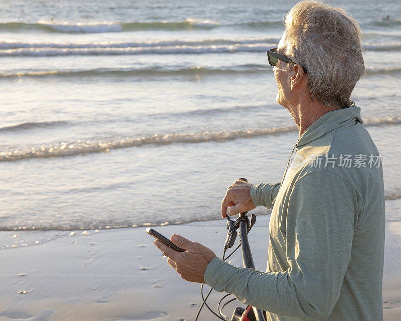 日出时，一名男子骑着自行车沿着空旷的海滩走