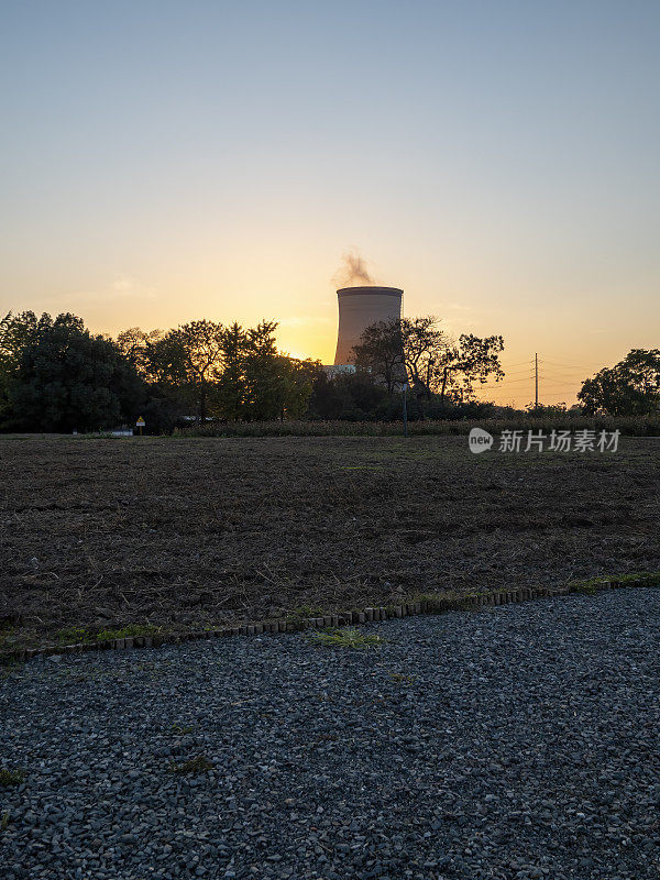 一座热电厂的冷却塔在夕阳中冒着蒸汽