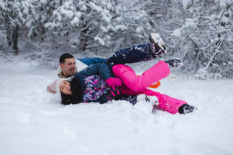 美丽的年轻情侣穿着五颜六色的衣服，在雪地上滑雪