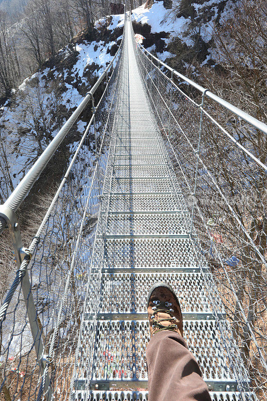 在不锈钢吊桥上行走的人的腿