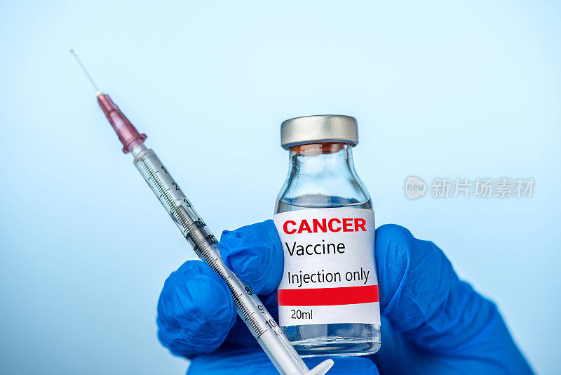 医生或护士拿着癌症疫苗，用她的蓝色手套注射。