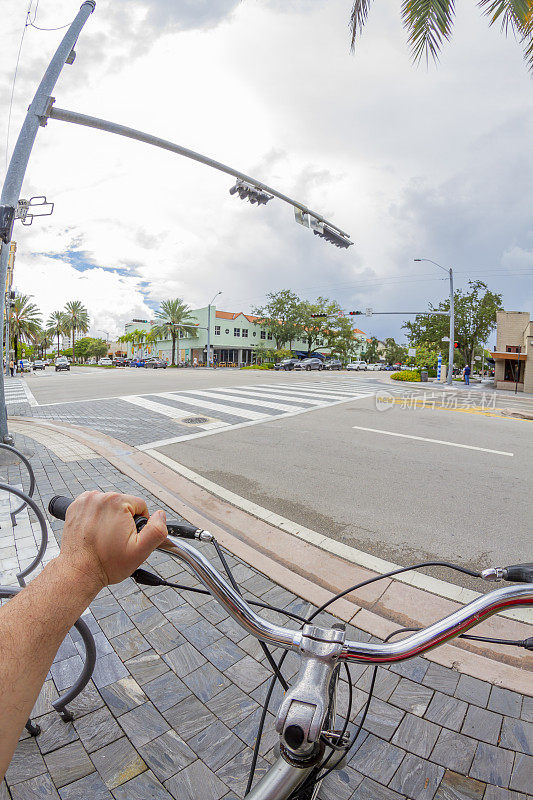 POV视角拍摄的年轻男子骑自行车在珊瑚山墙地区，迈阿密海滩，迈阿密，南佛罗里达州，美国。从个人角度拍摄异国情调的热带海滩旅游假期。