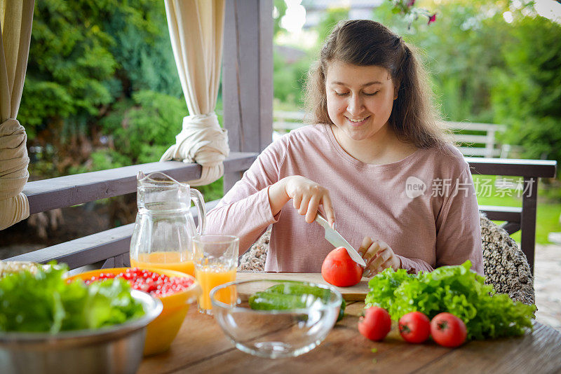 女人做新鲜的蔬菜沙拉，喝新鲜的橙汁