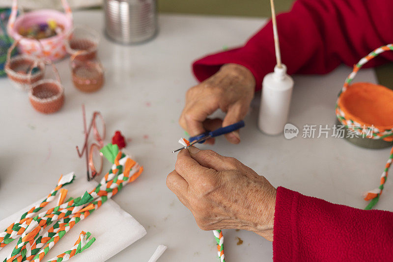 一位老妇人的手正在用材料制作工艺品