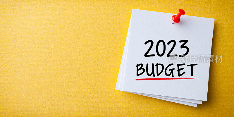 预算2023字在黄色纸板背景白色便利贴