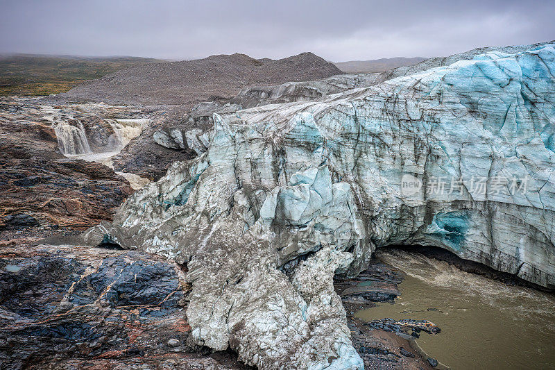 在多云的日子里，格陵兰岛拉塞尔冰川冰下的瀑布和隧道的鸟瞰图