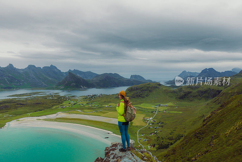 女性背包客从罗弗敦群岛的顶部凝视着海洋和山脉的风景