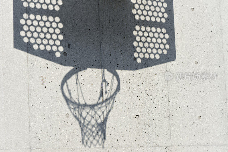 篮球框的影子映在白色的混凝土墙上