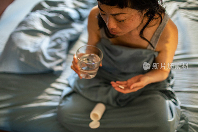 年轻的日本女人在卧室里吃药