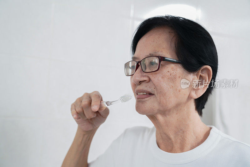 退休的亚洲妇女每天起床后刷牙。