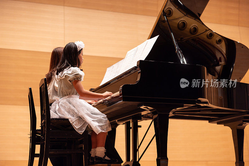 老师和学生在音乐会上一起弹钢琴