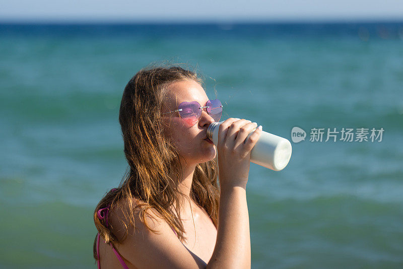 身着泳装的年轻女子喝水的特写镜头