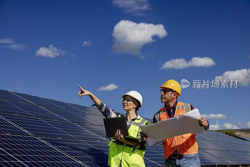 太阳能电池板和工程师工人在清洁电力农场工作。