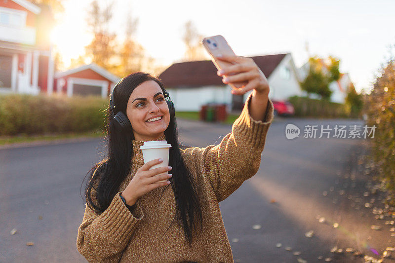 美丽的年轻女子在郊区户外自拍，听音乐