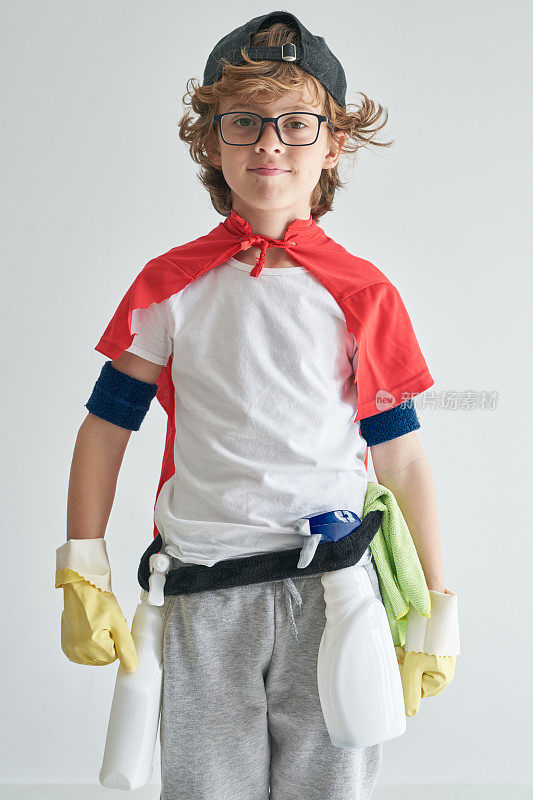 积极的男孩穿着戏服，拿着洗涤剂站在书房附近