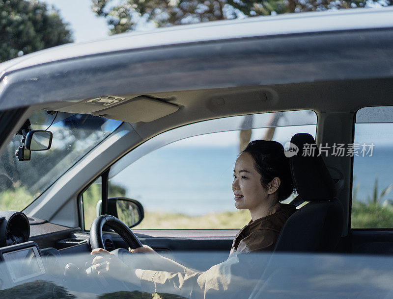 年轻的亚洲女子在阳光明媚的日子开车