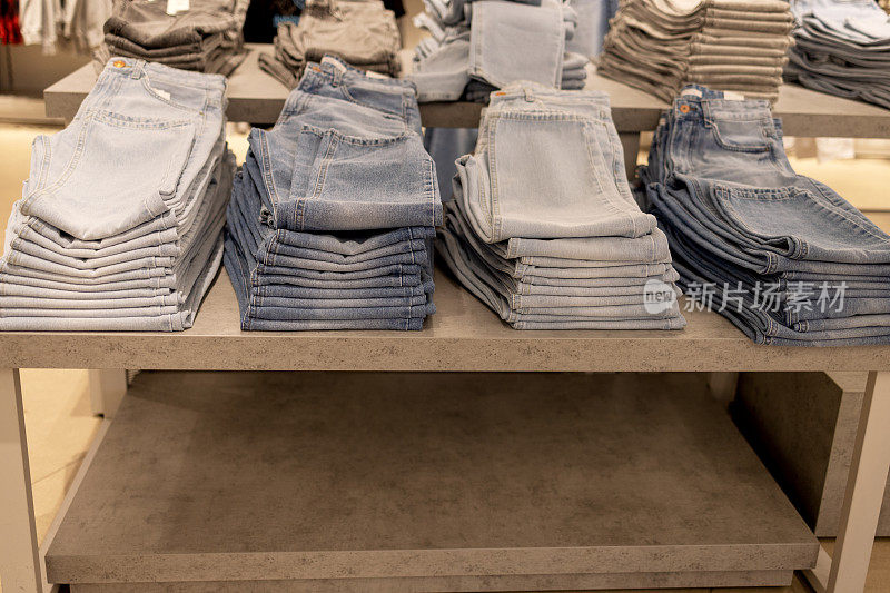 一排整齐地堆放在商店货架上的牛仔裤