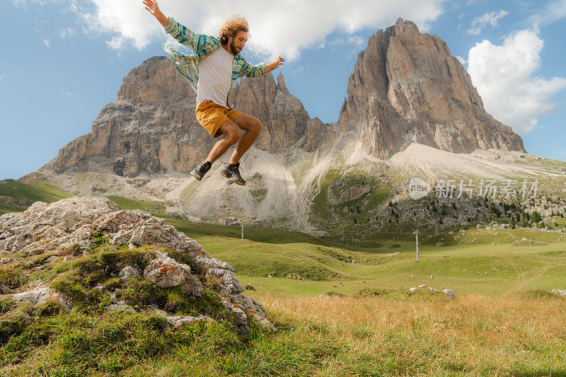 男子在多洛米蒂尖峰山脉的背景上跳跃
