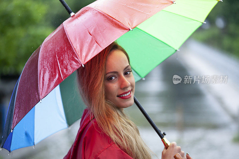 美丽的女孩拿着伞在雨中跳舞