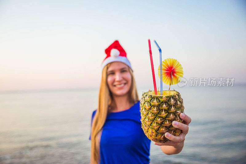 在海滩上戴着圣诞帽拿着鸡尾酒的女人