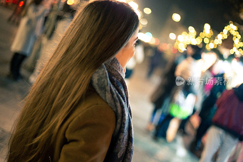 年轻女子晚上在圣诞市场