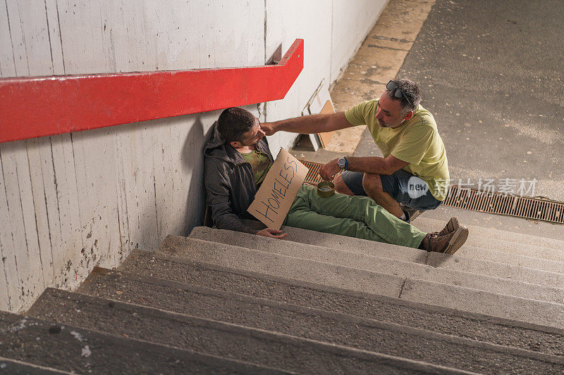 无家可归的乞丐正在接受一个好人的施舍