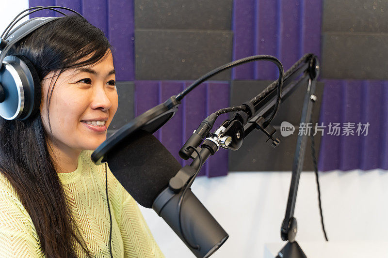 在广播演播室里戴着耳机的亚洲女性电台DJ