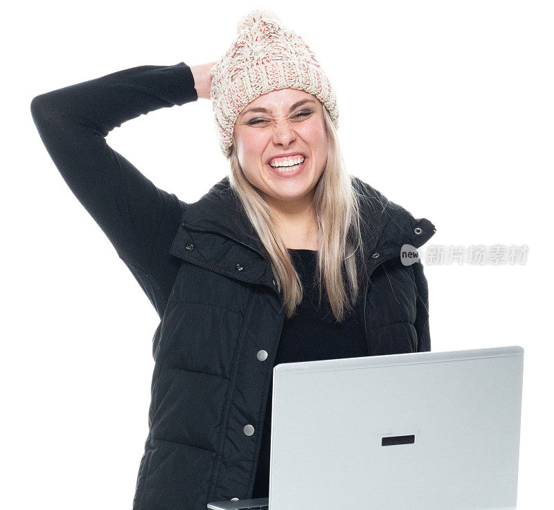 白人女性无袖蹲下，穿着暖和的衣服，使用笔记本电脑