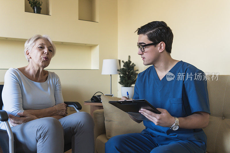 年轻医生正在给一位残疾老年妇女开处方